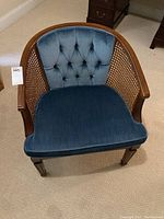 Front and side angle of blue velvet tufted barrel chair with wooden cane sides, showing overall condition and design details.