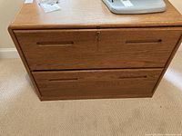 Front view of the Encore two drawer lateral file cabinet showing wood finish, drawer handles, and keyhole.