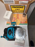 Photo showing all main contents of the nail kit including stamping tool, boxed item, packets, glass container, and pattern guide spread out on a surface.