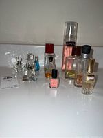 Nine assorted perfume bottles of various brands and conditions displayed on a white surface.