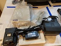 Photo showing Polaroid photo printer in white with cables and Polaroid Focal M 100 flash unit in black.