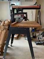 Front view of Sears Craftsman radial saw on metal stand with caster wheels, showing wooden work surface.