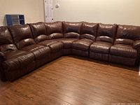 Front view of brown faux leather sectional sofa arranged in corner configuration on wood floor