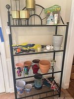 Metal shelving unit displaying various garden pots, decorative items, and small figurines arranged on the shelves.