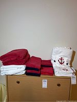 Photo of stacked red and white towels and nautical-themed washcloths on a dresser.