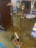 Full view of fireplace tool set showing andirons with duck head handles and grouping of shovel, brush, poker and tongs