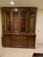 Full view of the two-piece Thomasville china cabinet showing upper and lower sections, wood finish, glass display, drawers, and doors.