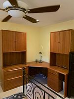 Full view of the L-shaped corner desk unit showing the wood tone, two hutch units on either end, drawers, and keyboard tray.