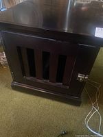 Front view of dark wood dog crate cabinet with vertical slats and metal latch on door