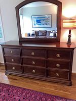 Front view of the six-drawer dresser with accompanying arched topped beveled mirror on top, showing minor surface wear and hardware details.