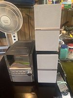 Panasonic stereo system alongside two matching speakers and a fan in background.