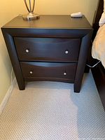 Full front view of dark brown nightstand showing two drawers and metal knobs