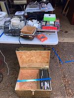 Overview of lot on table showing office supplies, storage items, and the brass file cabinet open with folders inside