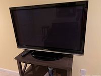 Front view of Panasonic 42 inch television on a stand with remote control beside it