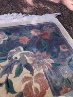 Close-up of the rug's floral pattern corner showing muted mauve, blue, and pink flowers with green leaves on a beige and blue background.