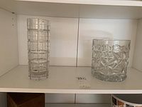Tall clear glass vase and short clear glass bowl with diamond cut pattern on shelf