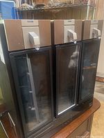 Front view of the three-chamber Sky Bar wine dispenser showing glass doors and metallic top dispensers