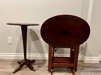 Full view of round accent table beside grouped folding TV trays in wooden stand