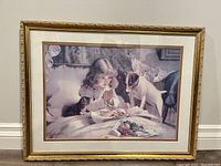 Framed art print 'Praying Girl' showing a young girl praying with a dog and cat nearby, in muted color tones, ornate gold frame visible.