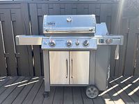 Front view of assembled grill showing lid, control panel, side shelves and wheels