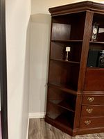 Photo of the finished wooden corner cabinet showing front and side details including shelves and drawers.