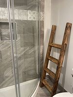 Photo of wooden ladder positioned near a shower, showing its rustic wood finish and three rungs.