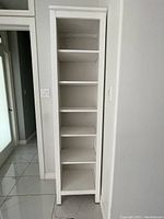 Front view of the white wooden display tower with six shelves, showing the structure and the open shelving.