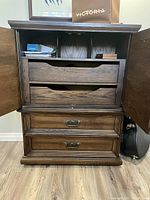 Front view of dresser/armoire showing open top cabinet doors, internal drawers, and two bottom drawers with metal handles.