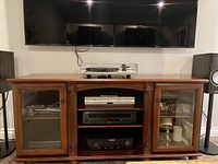 Front view of Bombay Co. entertainment centre showing glass-front cabinets, open shelves and carved accents