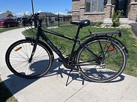 Left-side profile view of the black Genesis Trafik bike with rear rack, fenders, and bottle cage