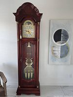 Frontal view of full grandfather clock showing dial, pendulum and weights
