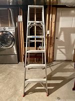 Front view of the 6 ft aluminum step ladder standing upright in a basement.