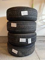Stack of four snow tires mounted on rims in a garage setting