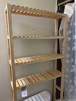 Photo showing full view of the light-colored wooden bathroom shelving unit with four slatted shelves.