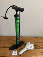 Photo of the green Bell Air Attack bike pump standing upright with black handle and base next to a white bicycle seat.