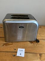 Side view of the Oster 2-slice toaster showing stainless steel finish and black power cord.