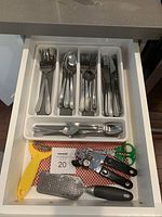 Full drawer showing utensil holder with various cutlery and additional kitchen tools.