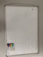 Full white board with five colored dry erase markers attached at the bottom left corner