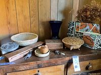 Overview of assorted small decorative items including vases, carved boxes, baskets, crystals, and metal figurines on a wooden cabinet