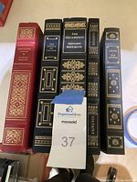 Photo showing the spine of all five leather-bound classic books with gold embossing.