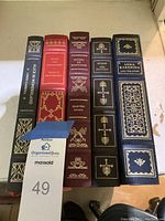 Spine view of five Franklin Library hardcover books: Alice in Wonderland, Crime and Punishment, Selected Essays, The Odyssey, Anna Karenina.