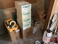 Photo showing multiple stacked boxes labeled GatorSkin high-grade flappers and nearby crates with plumbing parts and fittings, along with a white spray bottle.