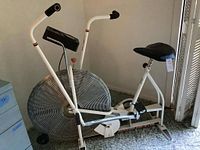 Side view of white Schwinn Air-Dyne stationary bike with black saddle and large front vented fan wheel.