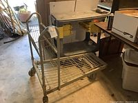 Metal cart with wire shelves and basket on wheels, showing side and front views.