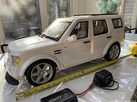 Side view of white 1/6 scale Land Rover Discovery RC model next to measuring tape