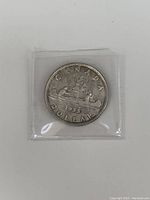 Front side of 1935 Canadian silver dollar depicting a canoe with two paddlers and the year 1935.