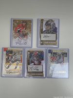 Front side of five autographed hockey cards in protective sleeves showing player images and signatures