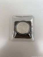 Silver coin in plastic holder, front view showing design details and denomination.