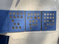 Open view of blue album with multiple Canadian nickel coins arranged in rows.