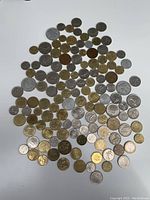 Overhead photo showing a large assortment of French coins in various sizes and metals spread out in a roughly triangular pattern on a white background.